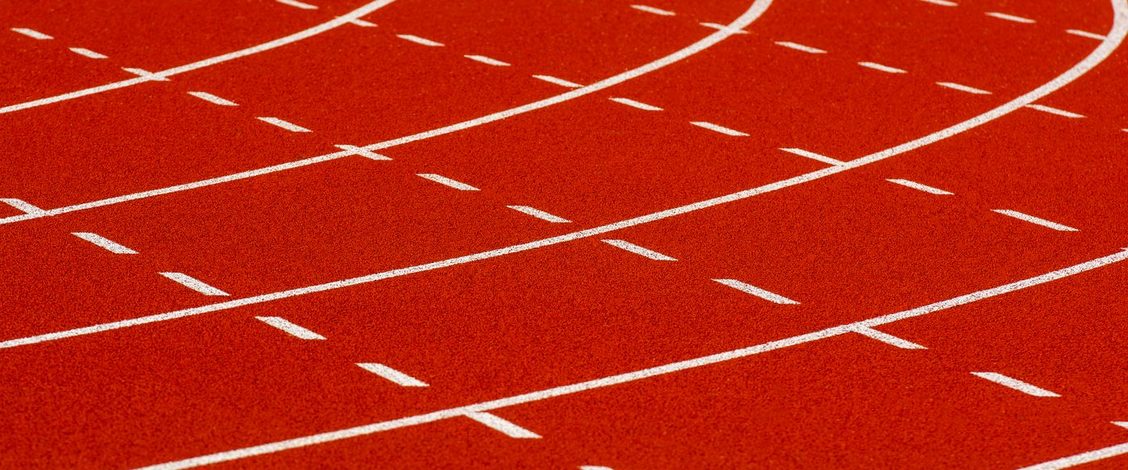 The curved red lanes of an athletics track marked out in white lines and dashes